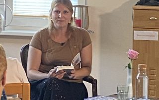 Eine Mitarbeiterin vom Hospiz hält ihr Buch in der Hand und schaut in die Kamera