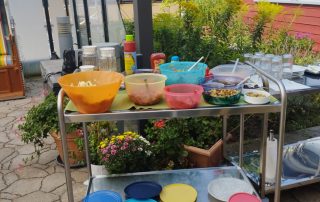 Ein Wagen mit Salaten und ein Wagen mit Geschirr, Besteck und Gläser stehen auf der Terrasse