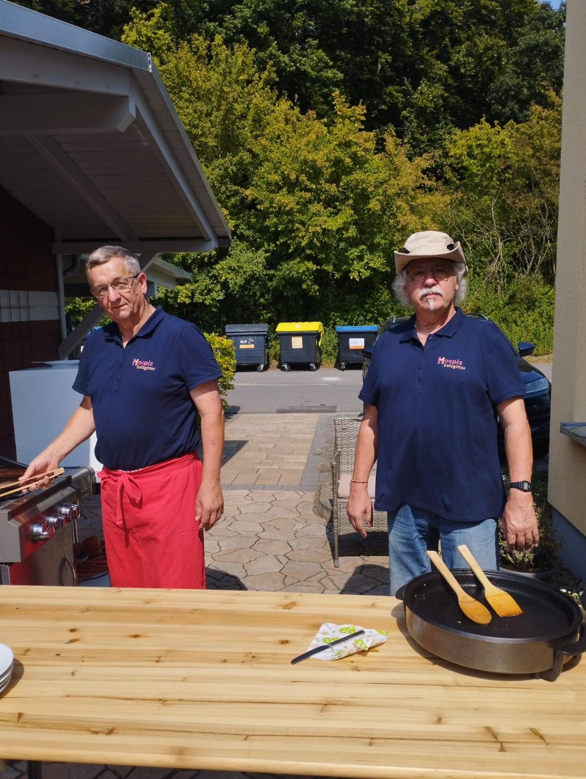 2 ehrenamtliche Hausmeister stehen am Grill 2 ehrenamtliche Hausmeister stehen am Grill