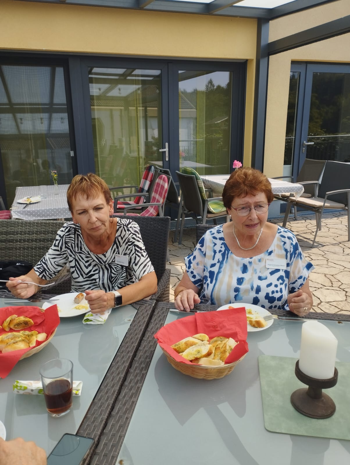 2 ehrenamtliche Mitarbeiter sitzen am Tisch auf Hospizterrasse und essen 2 ehrenamtliche Mitarbeiter sitzen am Tisch auf Hospizterrasse und essen