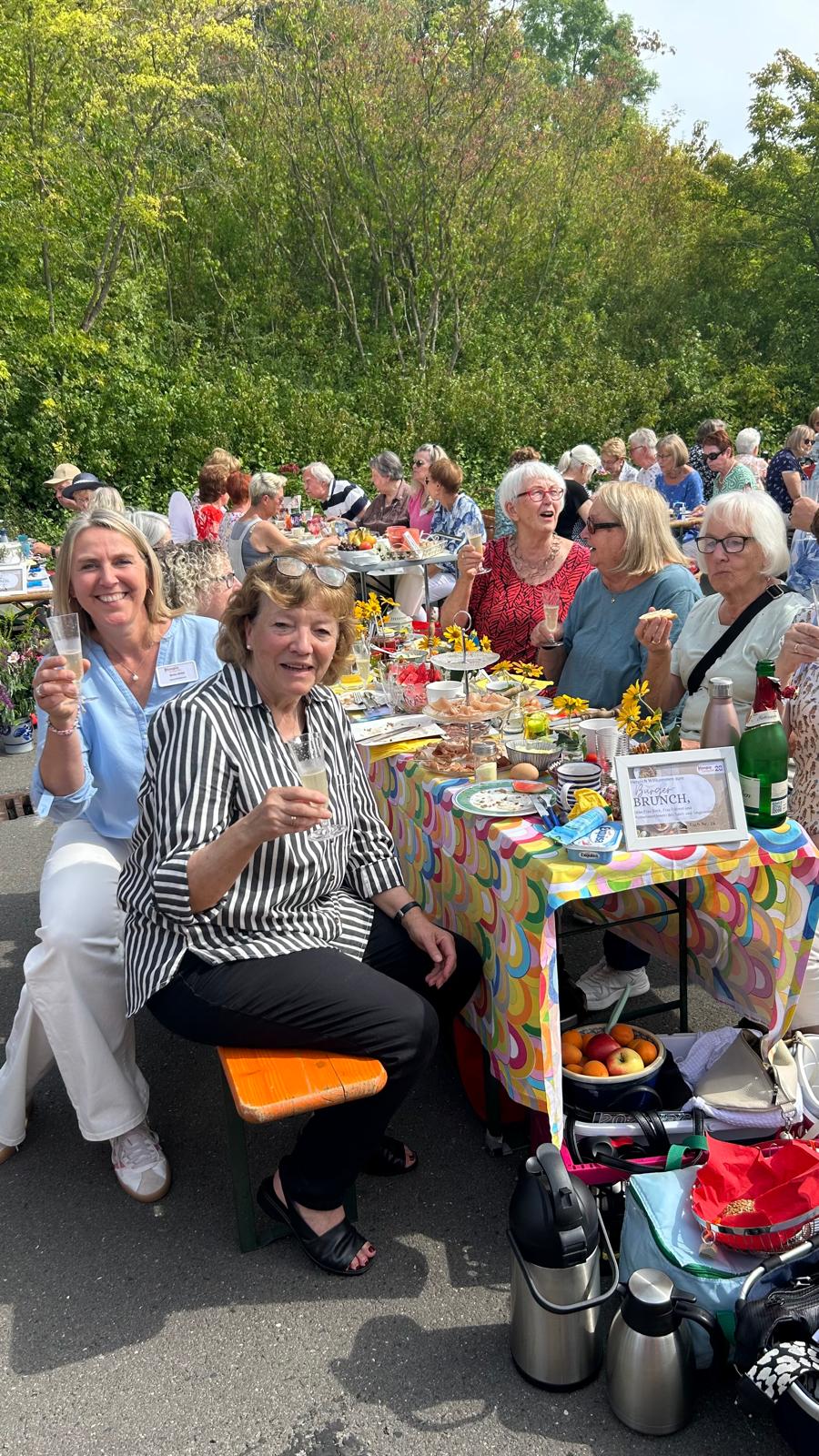Im Vorder- und Hintergrund sitzen viele Menschen essen und trinken Sekt