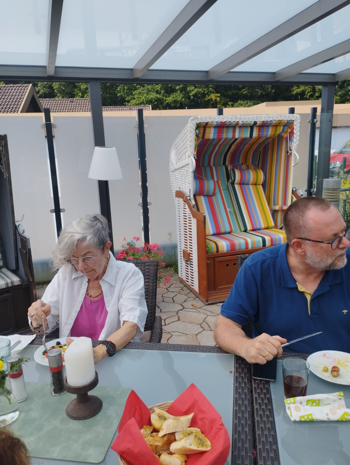 Frau und Mann sitzen am Tisch auf Hospizterrasse und essen Gegrilltes Frau und Mann sitzen am Tisch auf Hospizterrasse und essen Gegrilltes