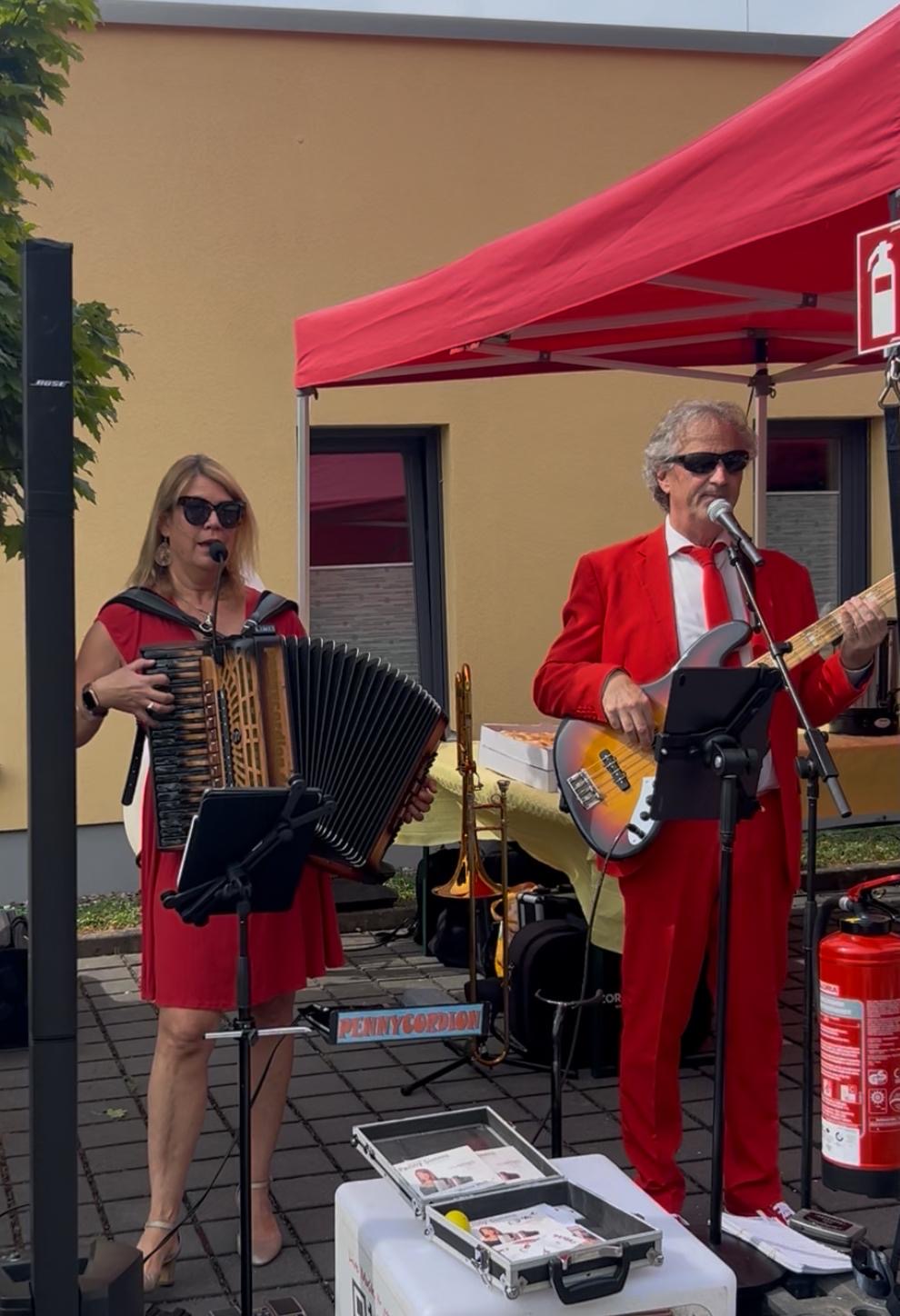 Eine Frau spielt Akkordeon und ein Mann spielt E-Gitarre vor dem Hospiz