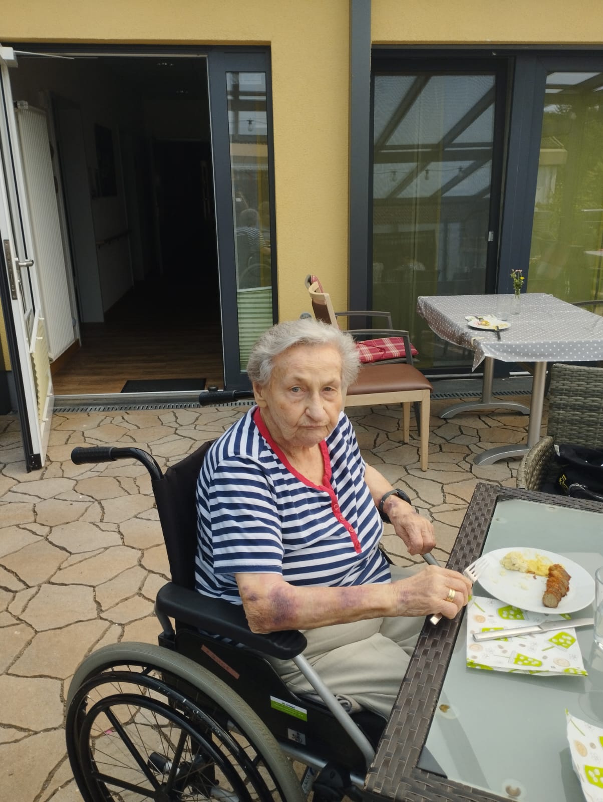 Ein Hospizgast sitzt im Rollstuhl am Tisch und isst Ein Hospizgast sitzt im Rollstuhl am Tisch und isst