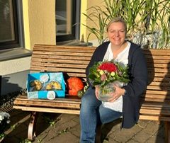 Pflegedienstleitung mit Blumenstrauß sitzt auf einer Bank