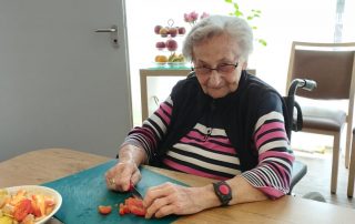 Frau am Küchentisch schneidet Gemüse