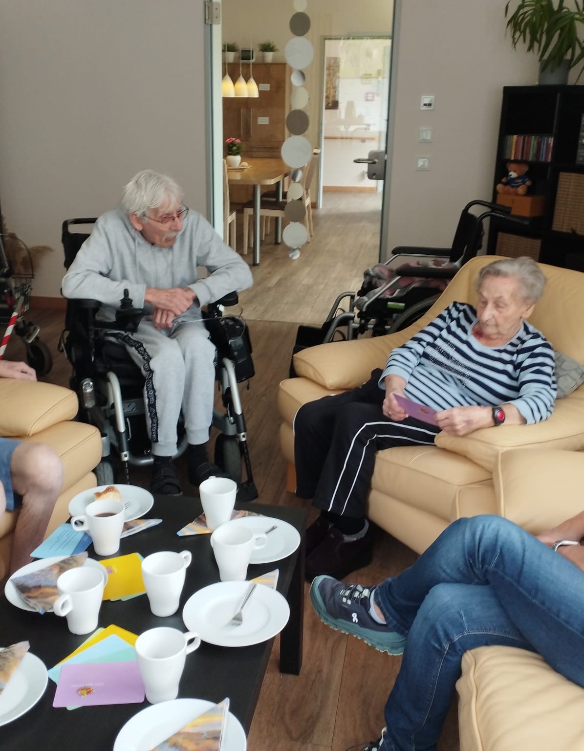 Mann und Frau sitzen bei gedecktem Kaffeetisch im Hospiz-Wohnzimmer