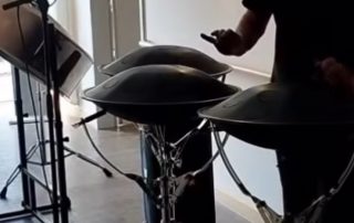 Mann macht Musik auf Steeldrums und Zungentrommel auf dem Hospizflur vor einem Gastzimmer