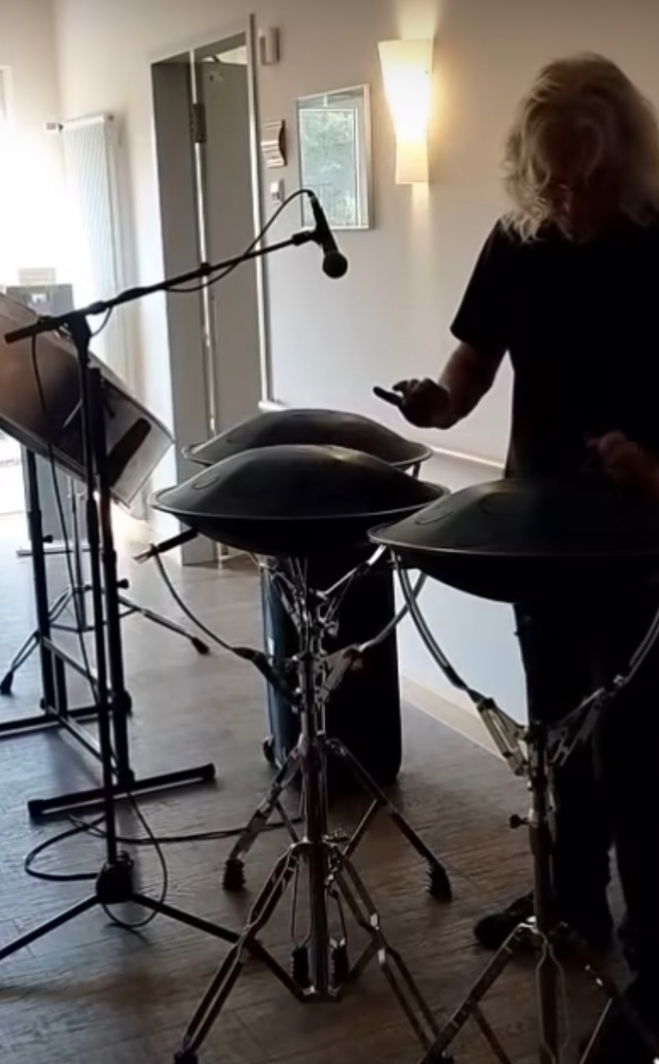 Mann macht Musik auf Steeldrums und Zungentrommel auf dem Hospizflur vor einem Gastzimmer