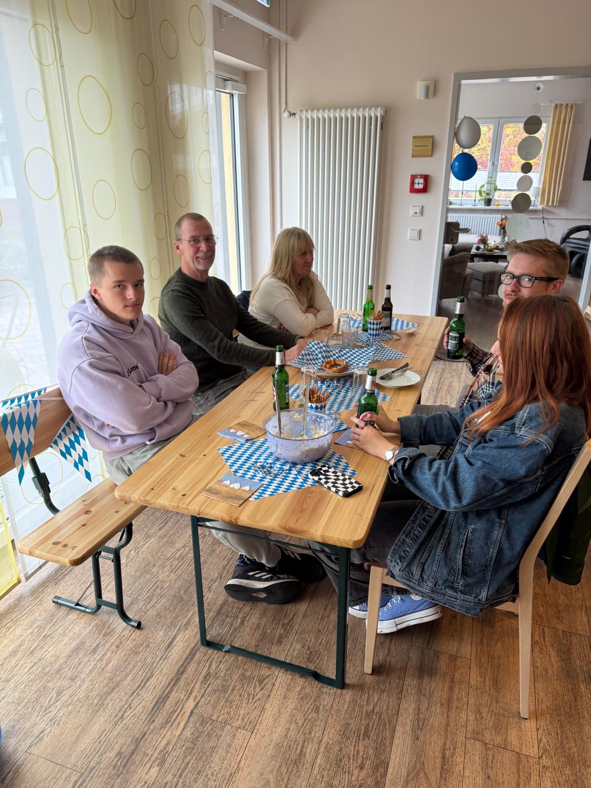 Menschen sitzen an gedeckter Bierzelt-garnitur und trinken und essen