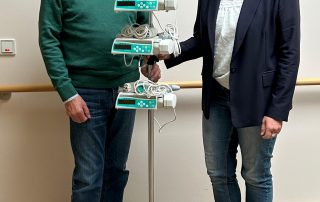 Geschäftsführerin und Spender stehen vor Perfusor im Hospizeingang