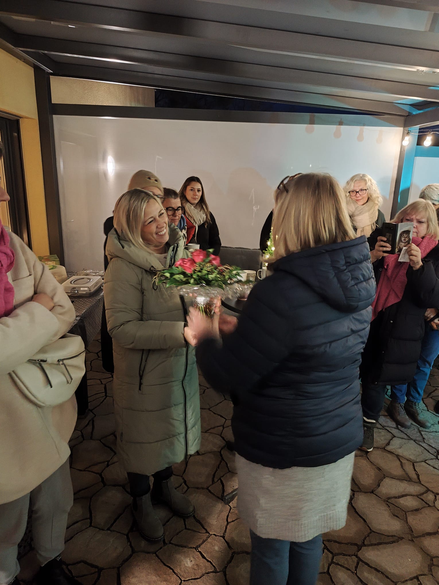 Frau übergibt einer anderen Frau einen Blumenstrauß