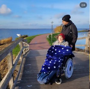 Ein Mann und eine Frau im Rollstuhl stehen auf einer Brücke am Meer