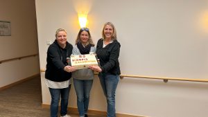 3 Frauen stehen mit Geburtstagskuchen im Eingang