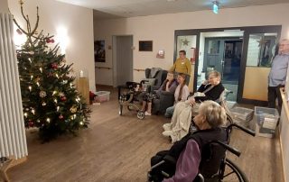 Mehrere Menschen betrachten den festlich geschmückten Weihnachtsbaum im Eingangsbereich