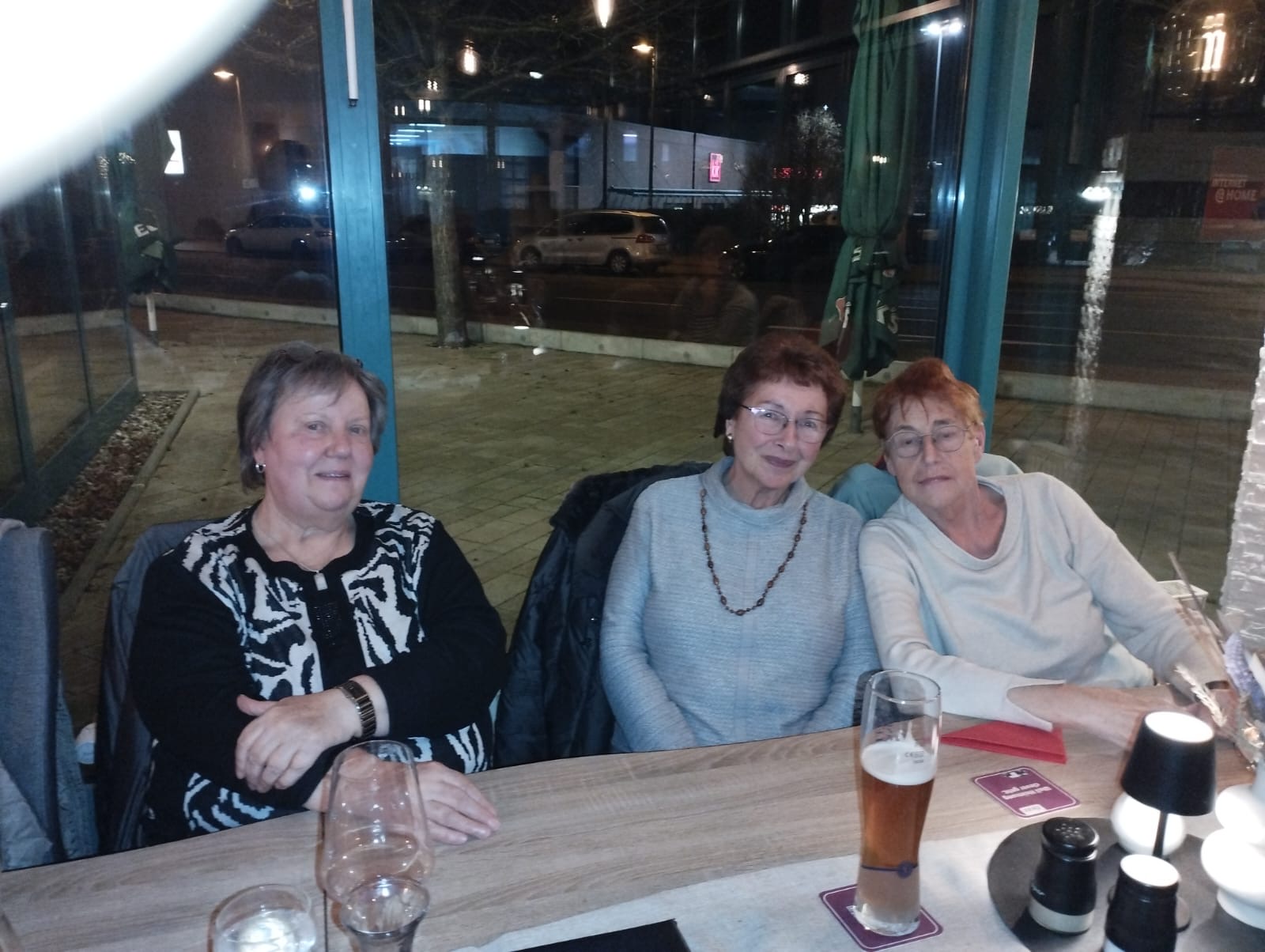 Drei Frauen sitzen am Tisch. Eine Frau neigt ihren Kopf zur Seite Drei Frauen sitzen am Tisch. Eine Frau neigt ihren Kopf zur Seite