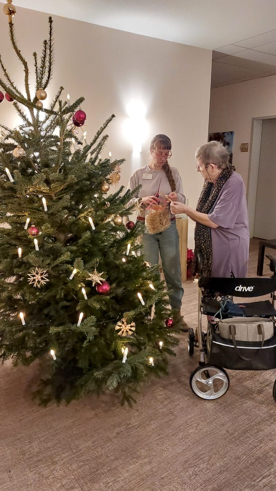 Zwei Frauen hängen Strohsterne an den Weihnachtsbaum