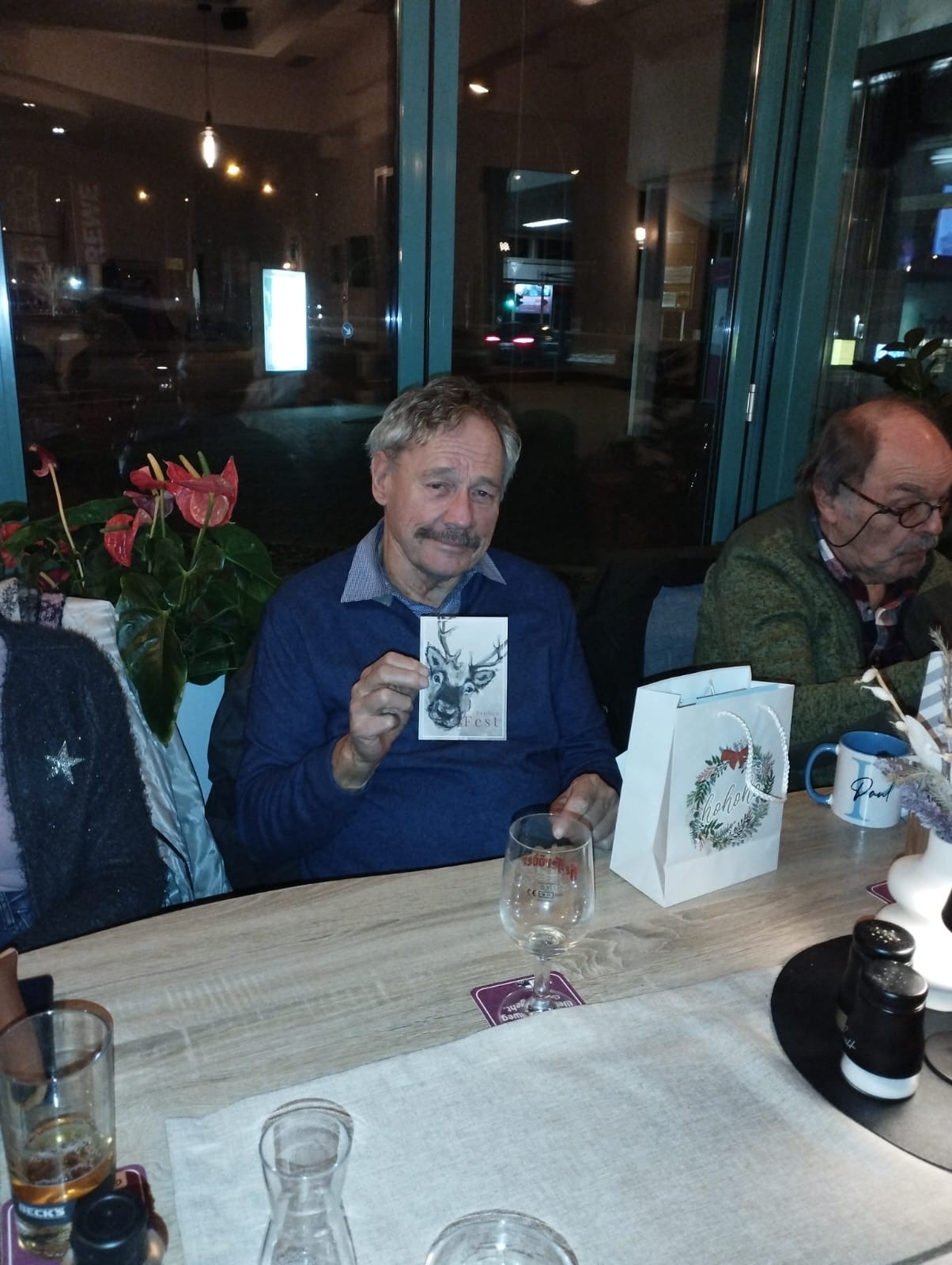 Ein Mann sitzt an einem Tisch und hält eine Karte hoch Ein Mann sitzt an einem Tisch und hält eine Karte hoch