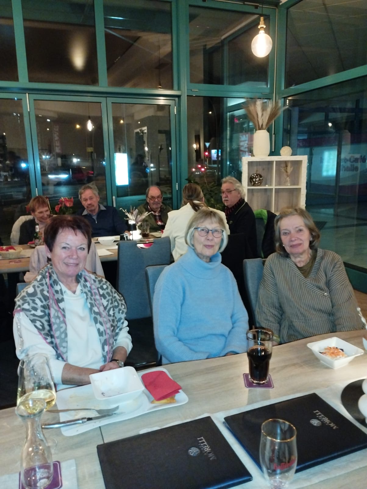 Drei Frauen sitzen am Tisch und auf dem Tisch stehen Getränke Drei Frauen sitzen am Tisch und auf dem Tisch stehen Getränke