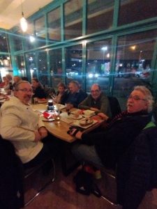 Vorne am Tisch sitzen 2 Männer, im Hintergrund sitzen 2 weitere Männer