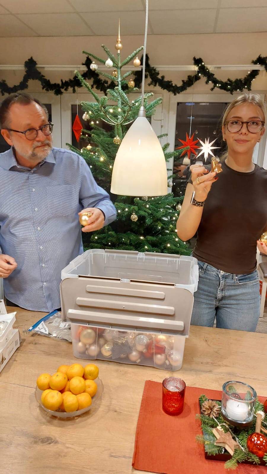 Eine junge Frau und ein Mann nehmen Weihnachtskugeln aus einer Kiste