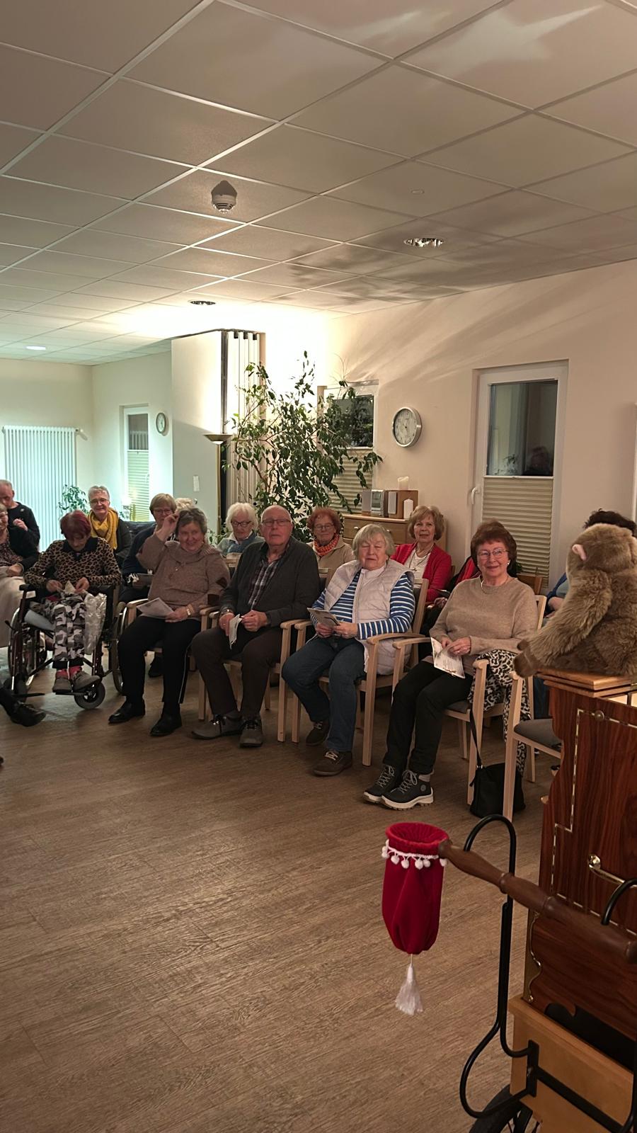 Mehrere Menschen sitzen in einem Halbkreis mit Liederzetteln in der Hand Mehrere Menschen sitzen in einem Halbkreis mit Liederzetteln in der Hand
