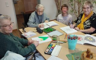 4 Frauen sitzen am Tisch und malen