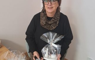 Portrait einer Frau, die ein Geschenk in der Hand hält. Auf dem Tisch steht ein weiteres Geschenk.