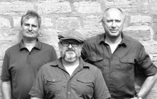 Portrait in schwarz weiß mit 3 Musikern der Band The BUZZ