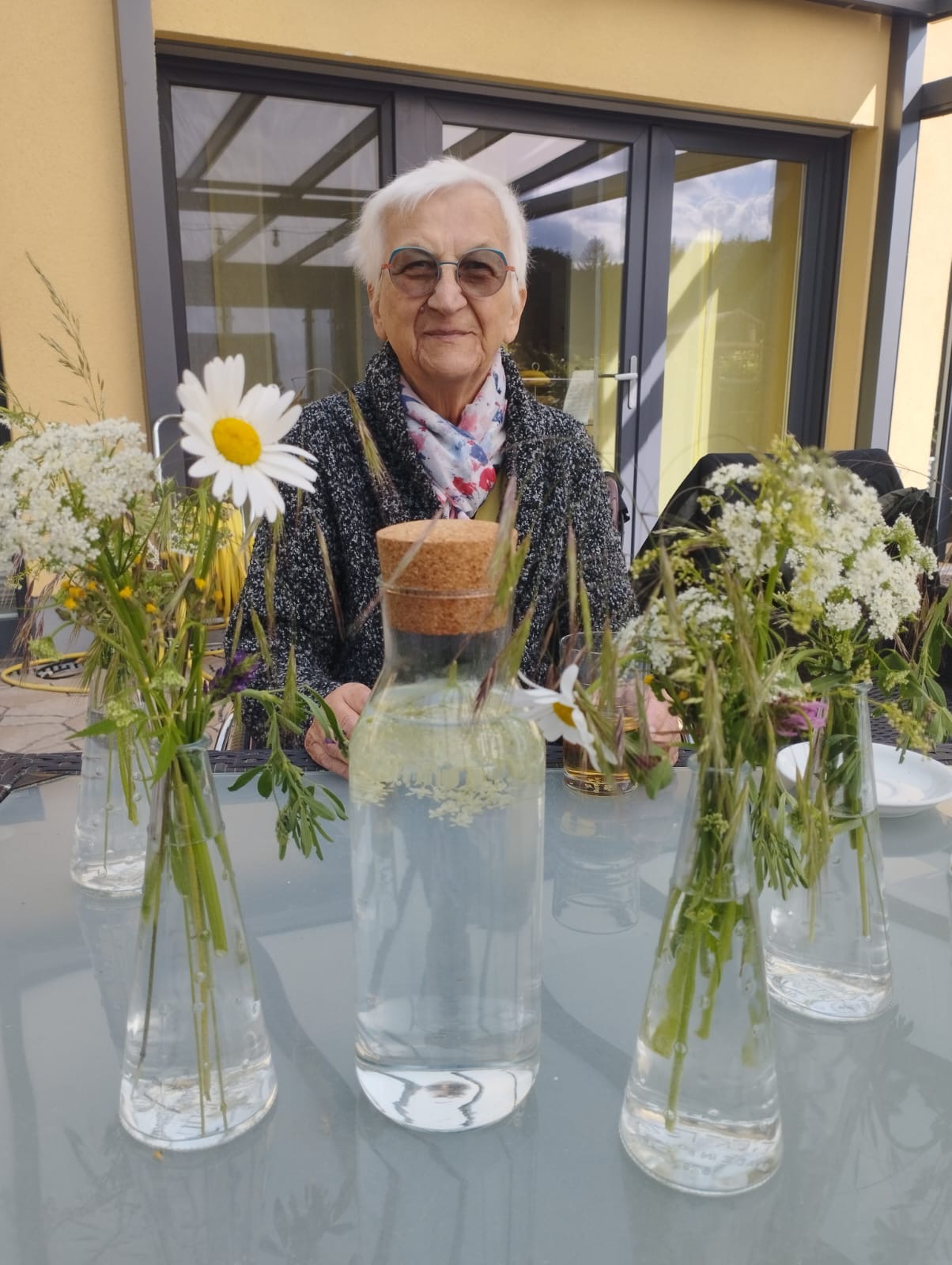 Gast sitzt am Tisch und schaut fröhlich auf die Blumenvasen Gast sitzt am Tisch und schaut fröhlich auf die Blumenvasen