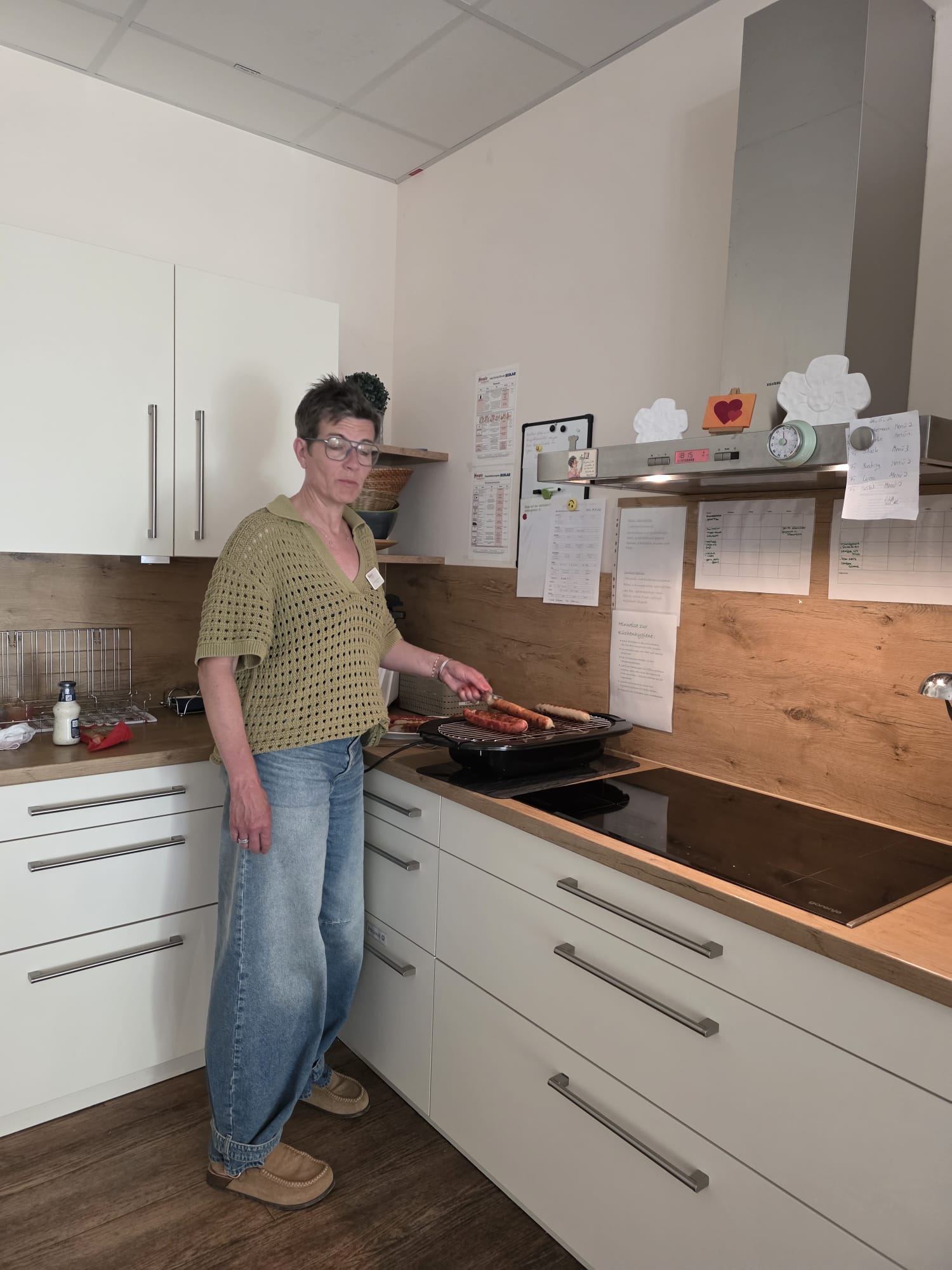 Ehrenamtliche Mitarbeiterin Yvonne Dremmler-Tillmann steht in der Küche am Elektro-Grill Ehrenamtliche Mitarbeiterin Yvonne Dremmler-Tillmann steht in der Küche am Elektro-Grill