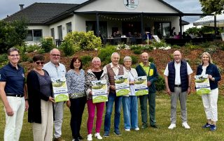 Spendenempfänger/-innen stehen mit einem Spendengutschein auf der Wiese