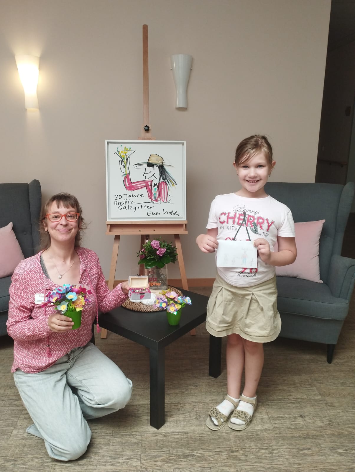 8-jährige Spenderin Romy und Mitarbeiterin Franziska Bahr (Sozialdienst) stehen im Eingangsbereich und halten die Spenden in den Händen