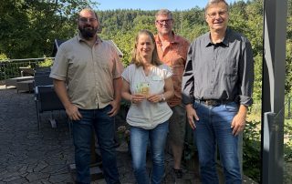 Volker Kammrath (Erster Vorsitz-ender), Richard Franklin (stellver- tretender Vor-sitzender), Martin Helling (Beisitzer) der Dorfgemein-schaft Gitter e. V. und Mitarbeiterin Jasmin Libich stehen auf der Hospizterrasse